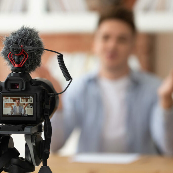 Close up professional digital equipment recording video blog of student Close up professional digital equipment recording video blog of student shown on screen man sit at desk in front of camera filming online training webinar educational seminar or job interview concept